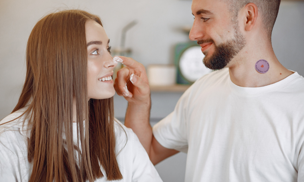 Man applying skincare cream to a woman's face while wearing a wellness patch, highlighting effective skin absorption and daily skincare.