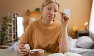 Woman sitting at a table with a wellness patch on her arm, representing natural dopamine support, focus, and mental wellbeing.