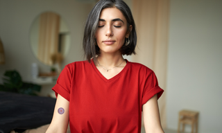 Woman meditating at home with a stress relief patch on her upper arm, illustrating a natural way to support relaxation, reduce daily stress, and promote emotional wellbeing.