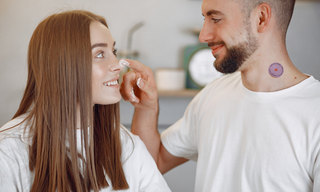 Man applying skincare cream to a woman's face while wearing a wellness patch, highlighting effective skin absorption and daily skincare.