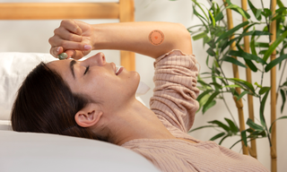 Woman relaxing with a wellness patch on her arm, representing calm, sleep support, and L-theanine wellness benefits.