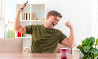 Man feeling energized and celebrating at a table with a visible energy patch on his arm, representing improved energy levels and cellular energy support.
