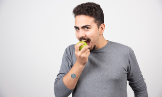 Man choosing a healthy apple snack, representing mindful eating and strategies to manage late-night cravings and appetite control.