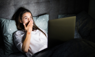 Night routine for better sleep showing woman using laptop in bed, highlighting screen time impact on sleep quality