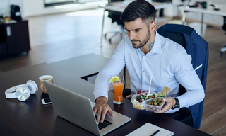 Busy work routine with healthy food, representing the struggle to maintain diet and weight management