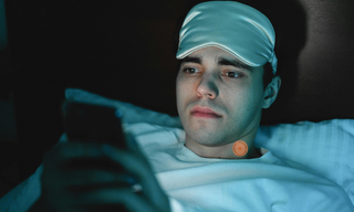 A man struggling to switch off at night while in bed, using a patch as part of a nightly wind-down routine.
