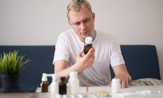 Man comparing traditional supplement bottles while considering switching from pills to nutrient patches for his daily wellness routine.