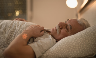 Senior man resting in bed while using a sleep patch, representing healthy sleep habits, nighttime recovery, magnesium for sleep, and wellness support for better rest.