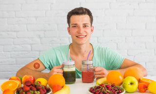 Man holding healthy fruit smoothies with fresh fruits on table, symbolizing natural energy, nutrition, and vitamin-rich diet