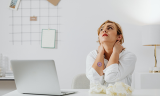 Woman experiencing chronic stress symptoms at work with neck pain