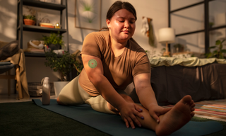 Woman stretching during a home workout routine, representing energy, recovery and lifestyle habits that support NAD+ levels.