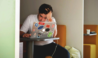 Man working on a laptop with a wellness patch on his arm, illustrating non-stimulant support during a midday energy drop.