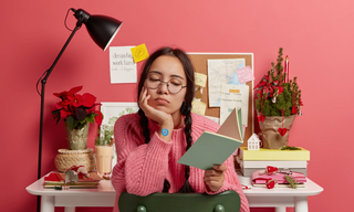 Tired woman at a desk during a busy week, representing the need for a simple everyday wellness patch routine for consistency